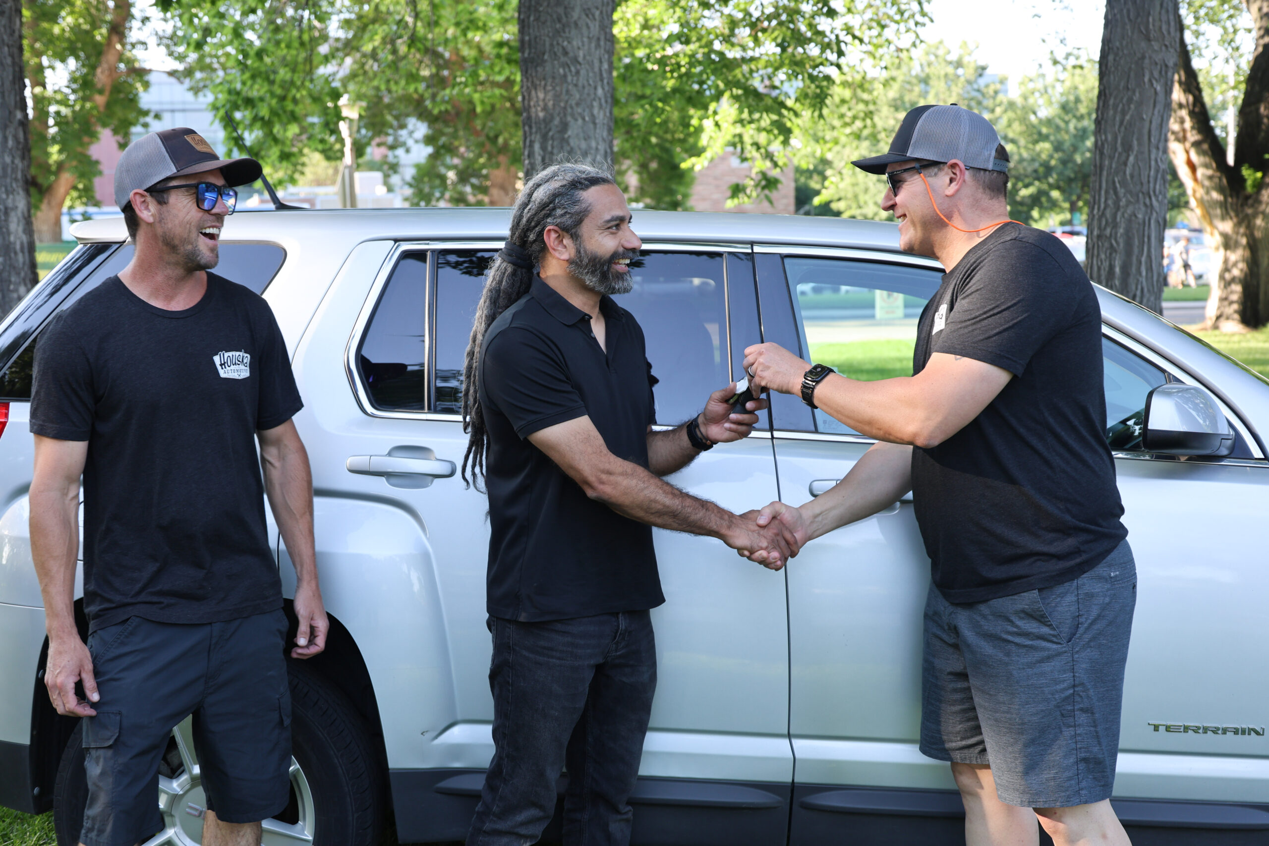 LJ Houska, grandson of Houska Automotive founder Chuck Houska, looks on as Lijo Joseph receives the keys to a 2012 GMC Terrain from Houska’s Jason Lightbody.