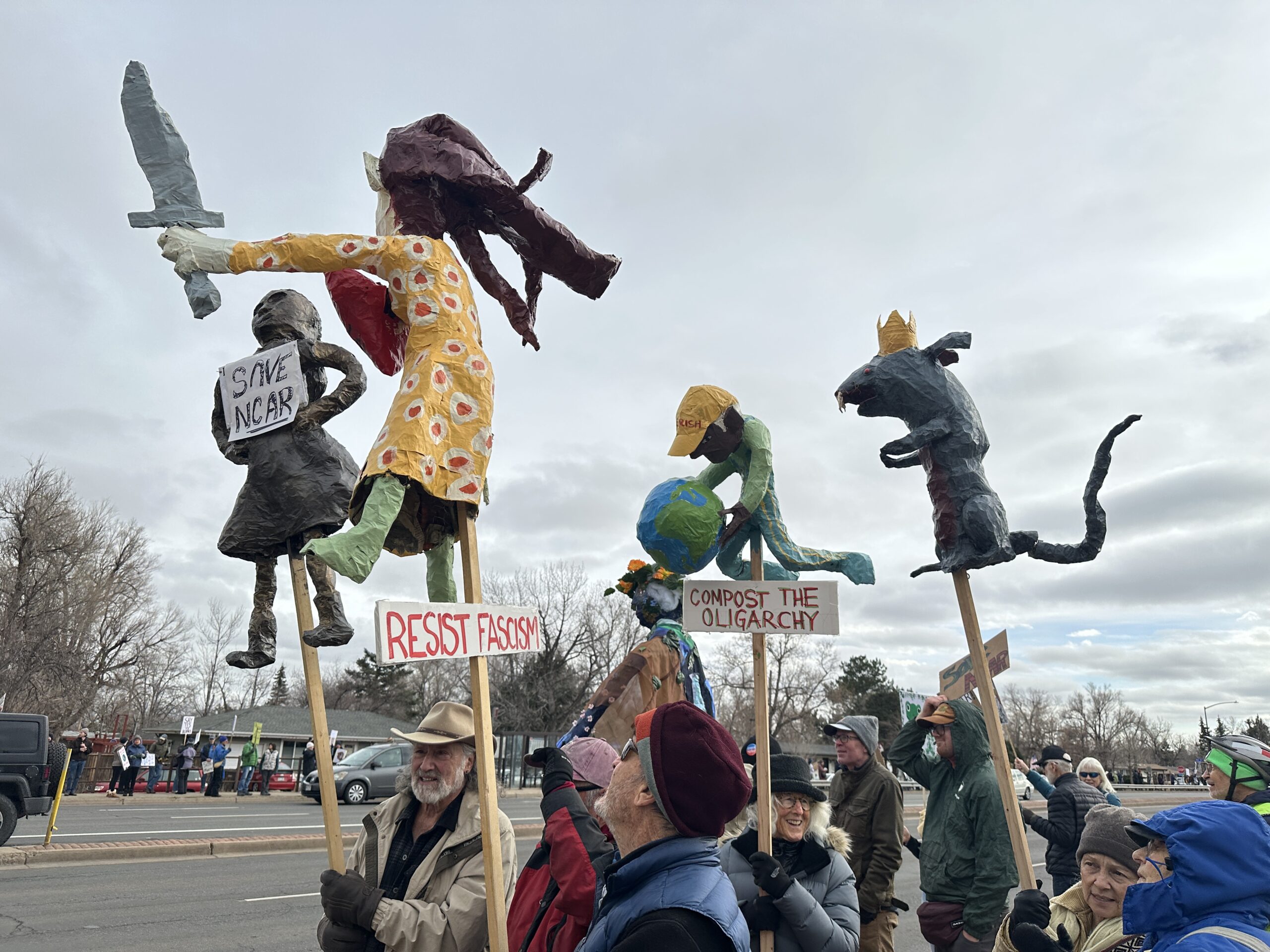 Protesters wave signs and figure at Saturday’s “Save NCAR Rally” in Boulder.