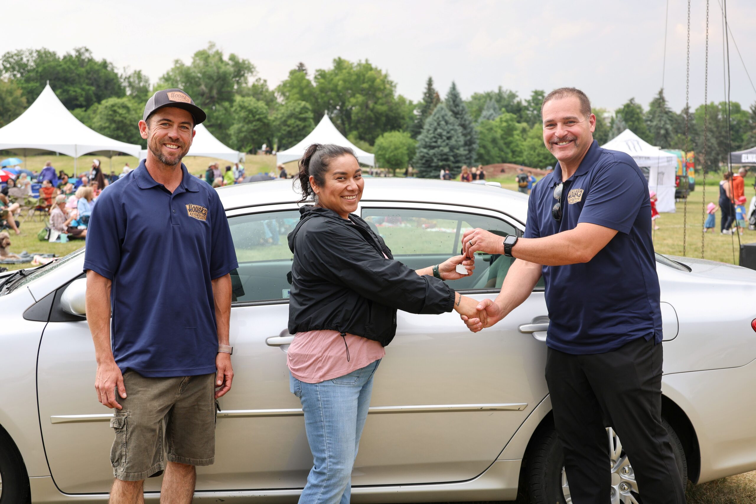 As L.J. Houska looks on at left, Lupe Ybarra is handed the keys to a 2010 Toyota Corolla by Jason Lightbody. Ybarra was selected by Project Sulf-Sufficiency to receive the car June 24 during Colorado State University’s Lagoon summer concert series.