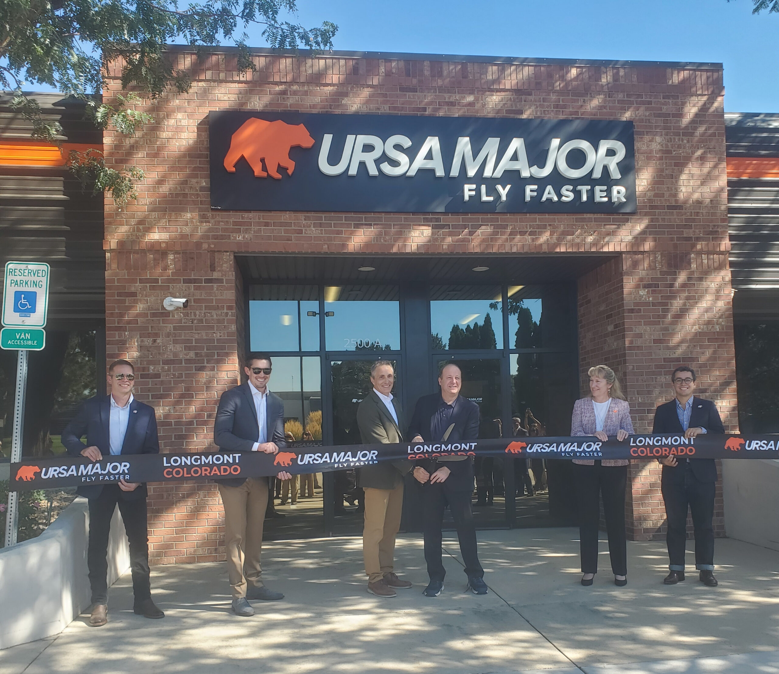 Surrounded by company officials, Ursa Major CEO Chris Spagnoletti looks on as Gov. Jared Polis prepares to cut a ribbon Thursday to open the manufacturer’s new facility in southwest Longmont. Dallas Heltzell/BizWest.